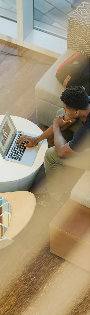 ソファーに座りMacBookをで作業する男性を上から写した画像