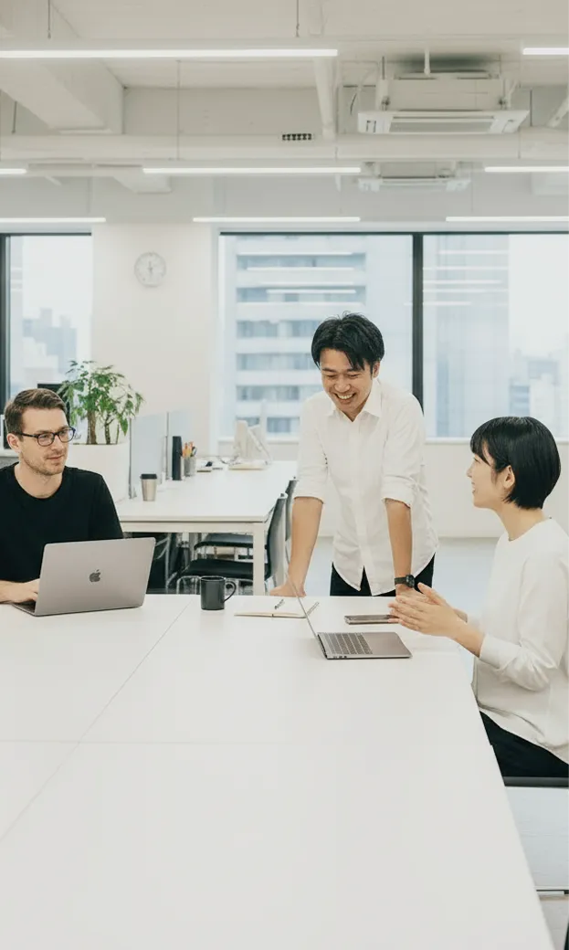 椅子に座っている女性と外国人男性、立っている男性が三人で談笑している