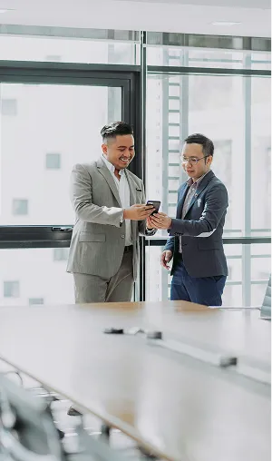 長机奥、窓際で男性二人がiPhoneを見ながら話している